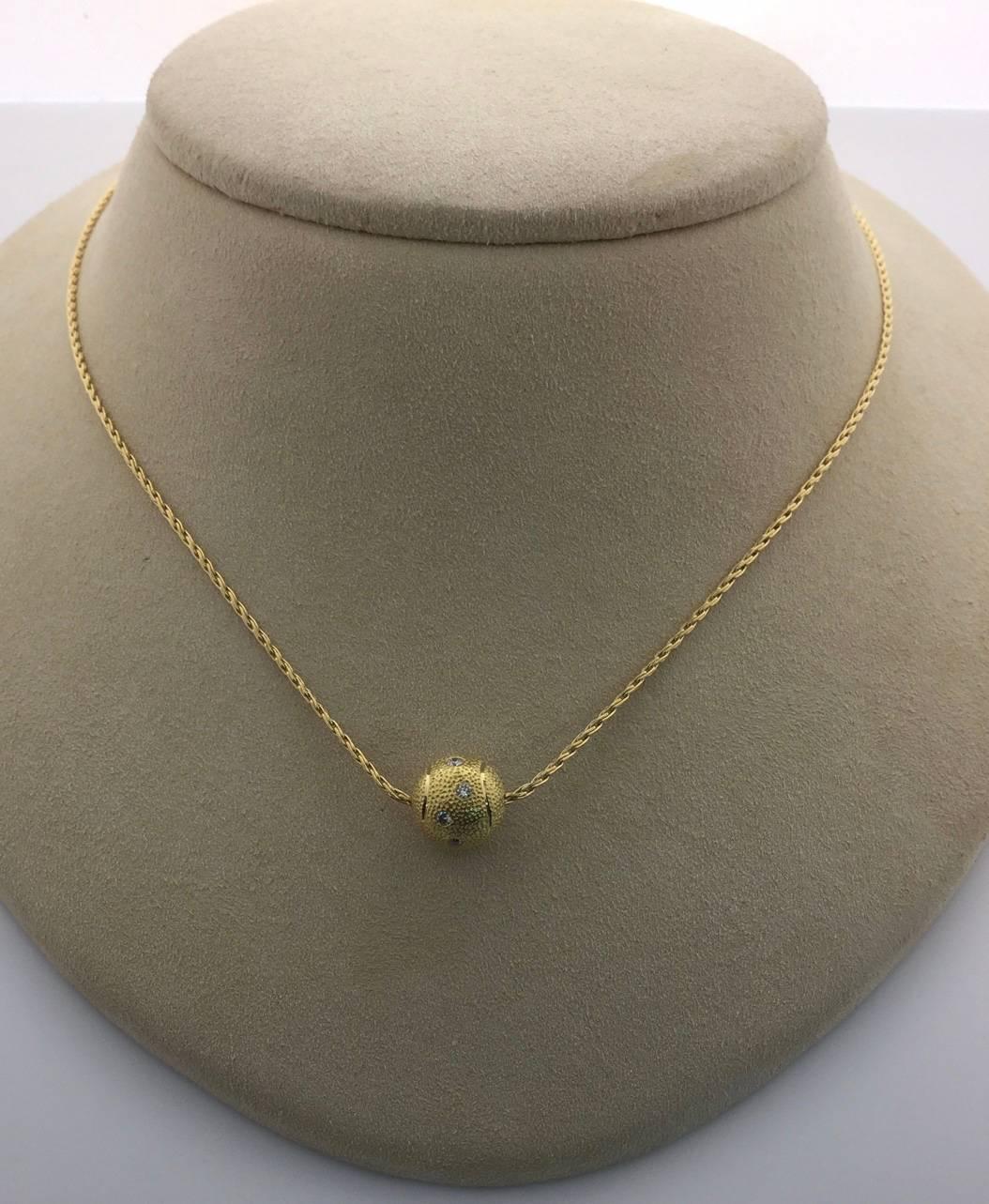 18K yellow gold tennis ball pendant containing 7 diamonds weighing combined 0.14 carat on a 16