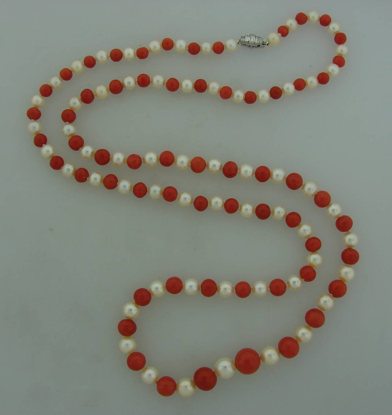 Elegant and classy bead necklace created by Buccellati in Italy in the 1980s. Features sixty one Mediterranean coral beads alternating with sixty two Akoya pearls and culminating with a beautiful white gold and diamond clasp. The pearls are around 7