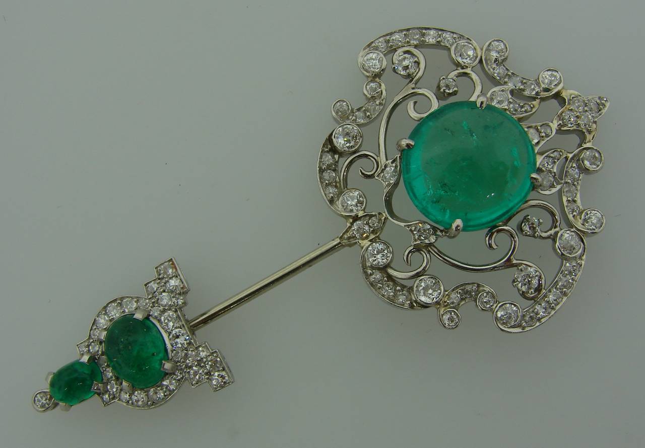 Gorgeous emerald, diamond  platinum assemblage pin created by Cartier in the 1920's. Features three cabochon emeralds set in a beautiful openwork platinum and diamond setting. 
The emeralds weigh approximately 8.20, 1.18 and 0.53 carats - total