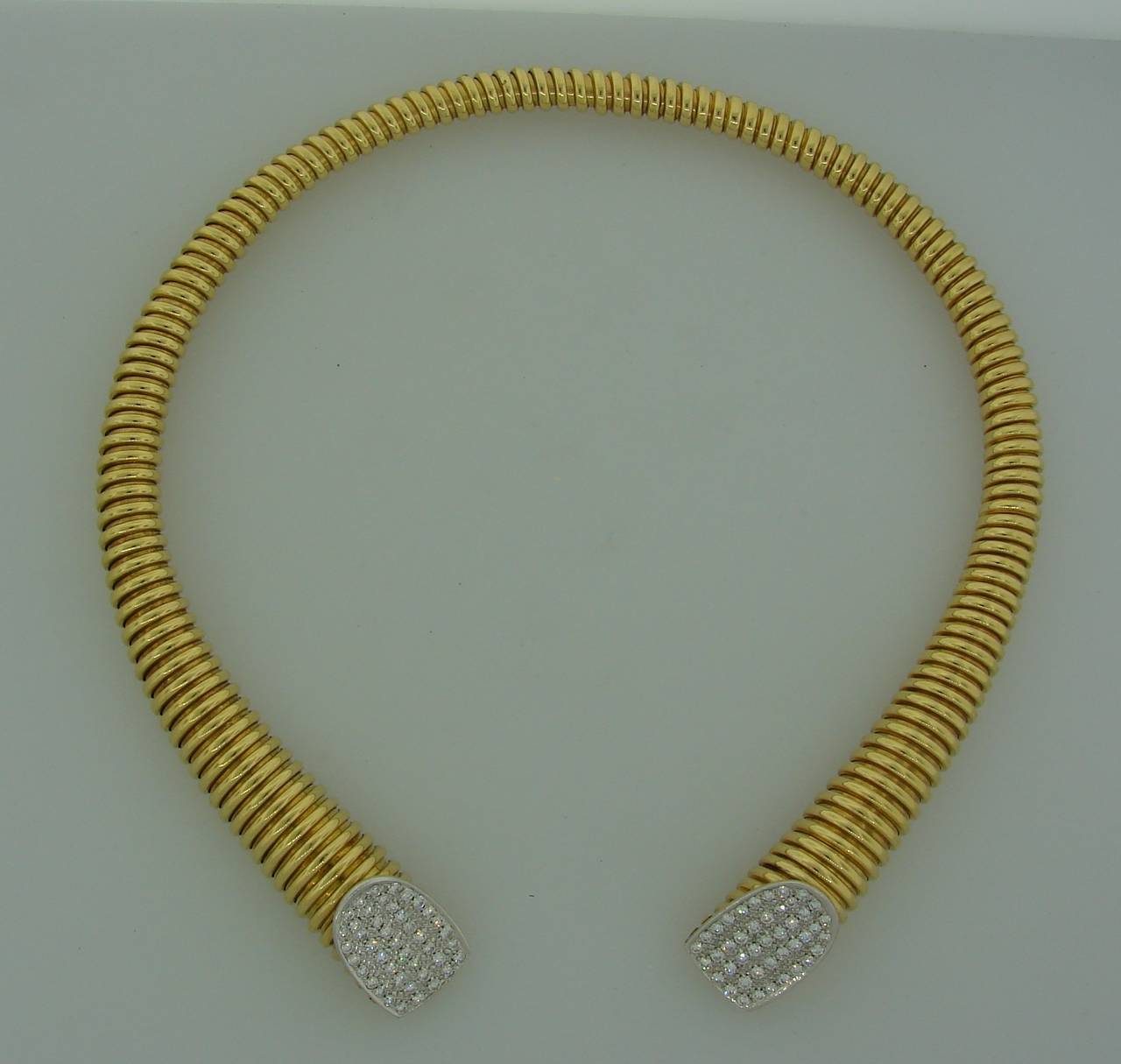 Stunning elegant tubogas choker necklace created by Cartier in Italy in the 1970's. The necklace is made of 18k yellow gold, the ends are accented with round brilliant cut diamonds set in 18k white gold. 

The necklace is 1/2