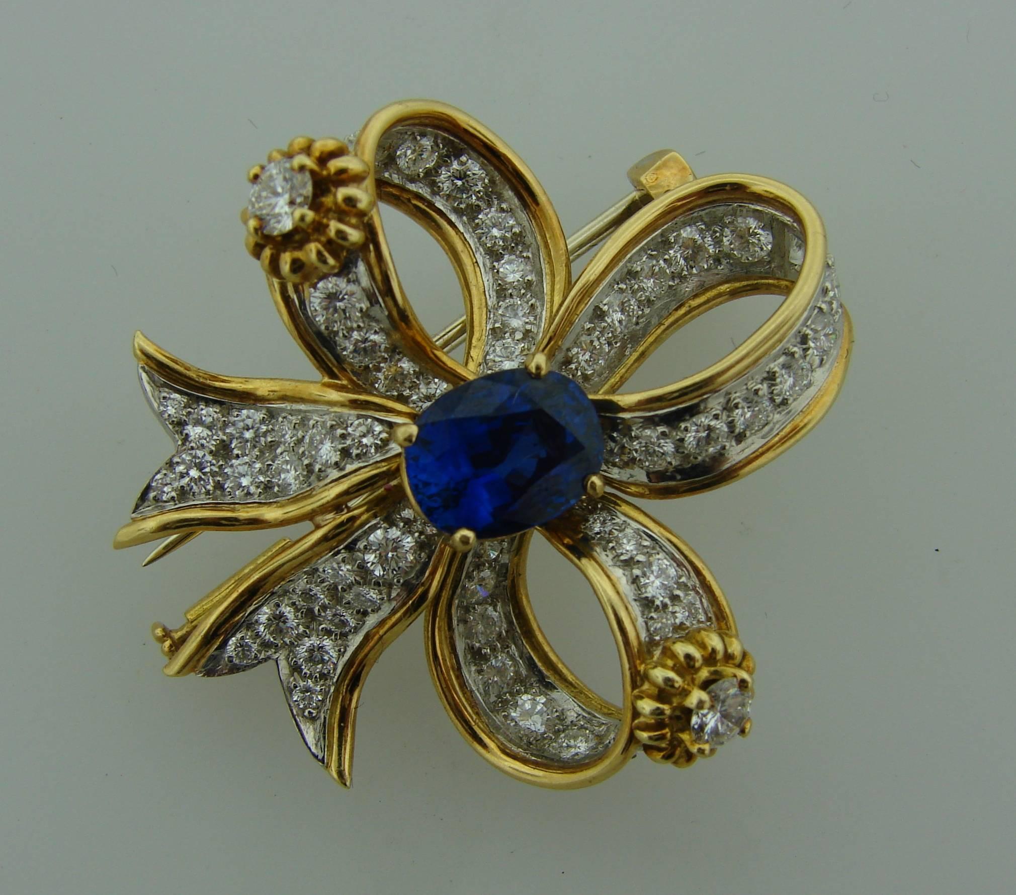 Lovely clip created by Jean Schlumberger for Tiffany & Co. in the 1950s. Designed as a beautiful bow and features a sapphire set in 18 karat (stamped) yellow and white gold set with round brilliant cut diamonds. The sapphire is oval shape, faceted,