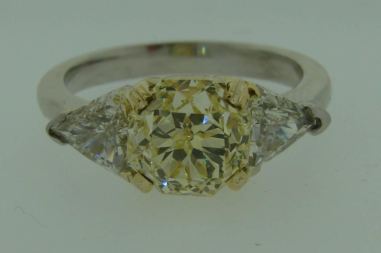 Classy and timeless three-stone ring - perfect engagement or anniversary ring. Features a 3.10- carat natural fancy yellow octagonal brilliant cut diamond flanked with two triangle-shape (called trillion) white diamonds. The fancy yellow diamond