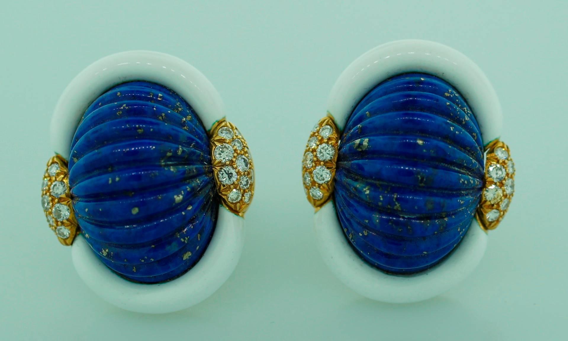 Colorful and prominent clip-on earrings created by Andrew Clunn in the 1980's. They feature carved lapis lazuli framed in white enamel and accentuated with diamonds on the sides. Beautiful color combination, volumetric shape and elegant carving are