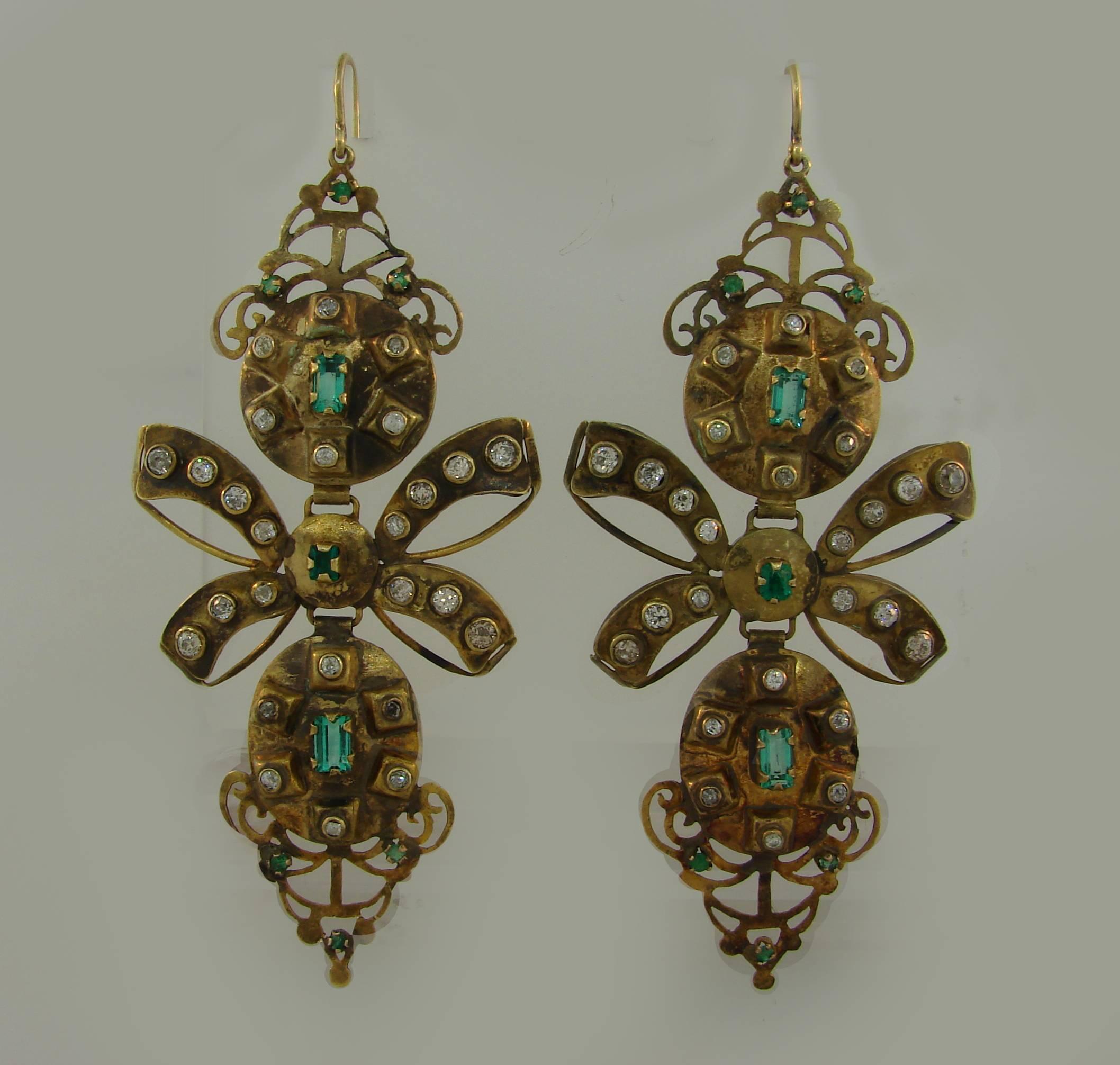 Dramatic yet wearable earrings created in the 1800s. 
They are made of 12 karat (tested) yellow gold and set with emeralds and old mine cut diamonds. Aged patina on gold accentuates antiquity of the earrings, the emerald cut of the emeralds keeps