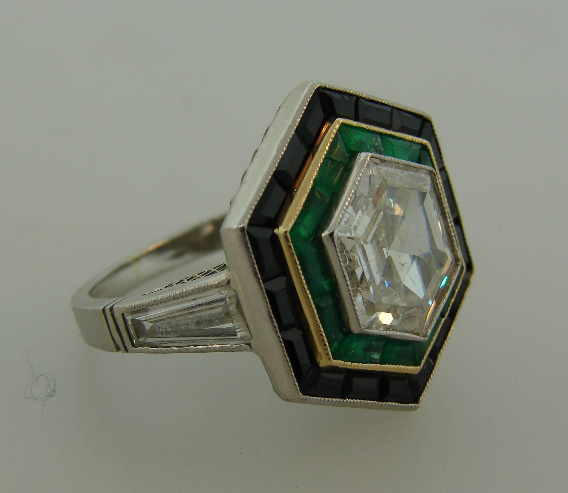 Gorgeous Art Deco Revival ring. An unusual cut diamond in hexagonal shape framed with a row of pre-cut emeralds and a row of pre-cut black onyx. The beautiful openwork setting is made of platinum  and accented with two tapered baguette cut diamonds.