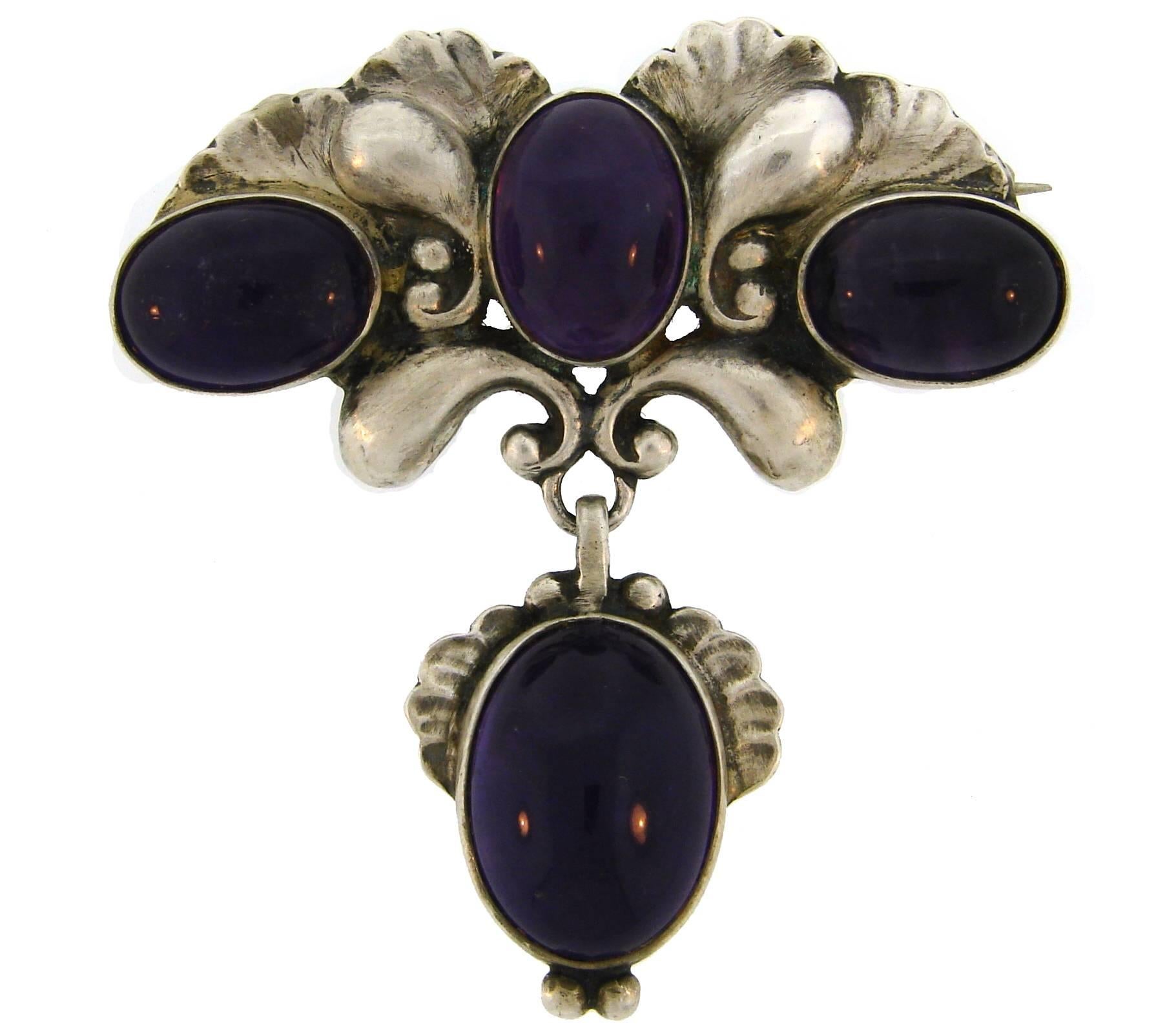 Lovely brooch created by Georg Jensen in Denmark.
It is made of sterling silver and amethyst. 
The brooch measures 2 x 2 inches (5 x 5 cm) and weighs 24.9 grams.
Stamped with Jensen maker's mark, a serial number, a country of manufacture, a