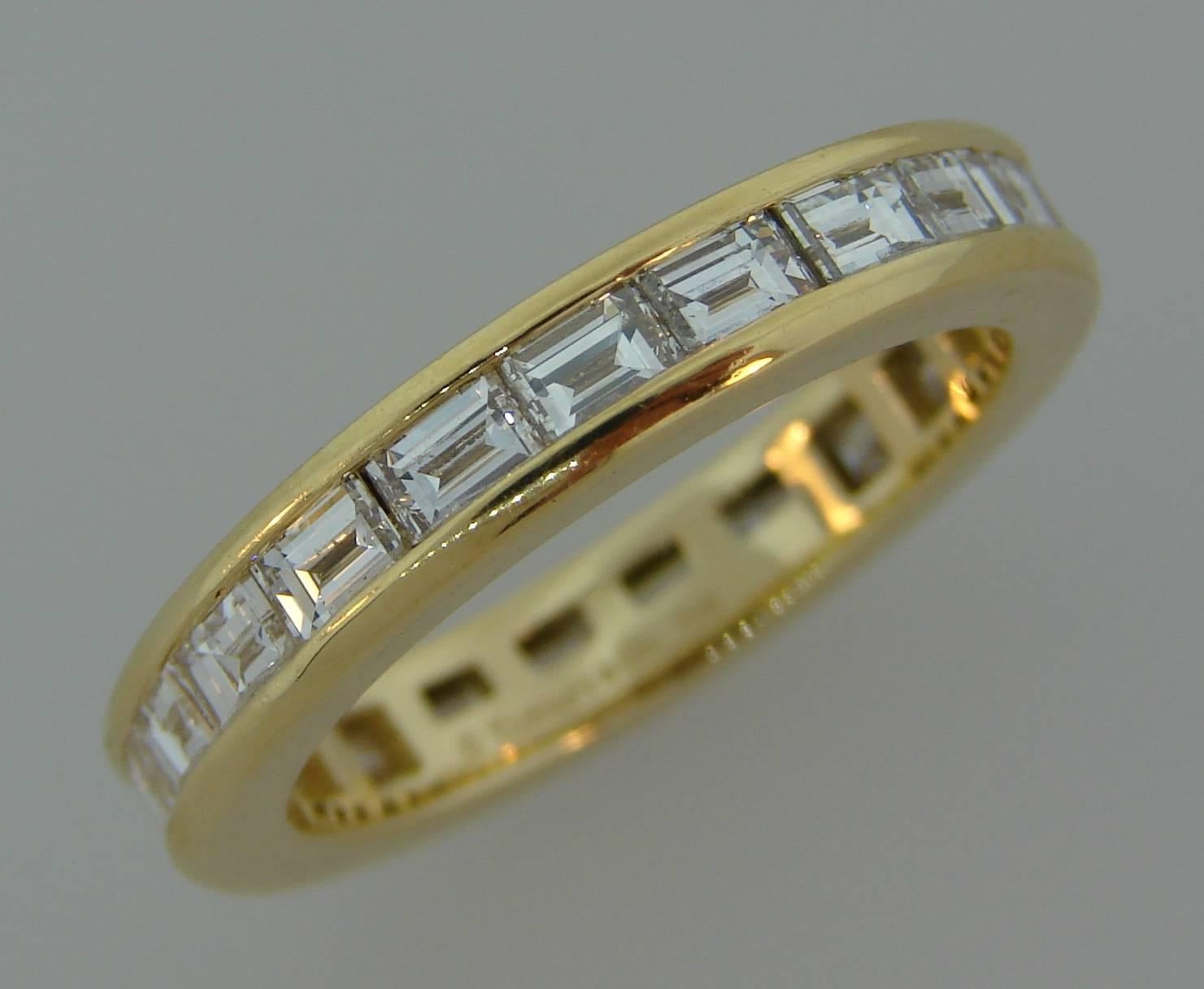 Classy and timeless eternity band created by Tiffany & Co. 
It is made of 18 karat yellow gold and twenty one horizontally set baguette cut diamonds (F-G color, VS1 clarity, total weight approximately 2.10 carats). 
The band is size 5.5. It is