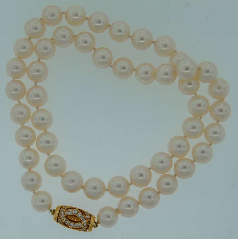 Elegant and timeless pearl strand necklace created by Cartier. Features 48 white round Akoya pearls and yellow gold clasp with round diamonds. The diamonds are set as a famous Cartier double 