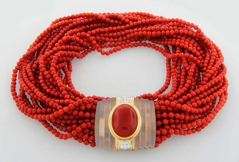 Stunning coral bead necklace created in Europe in the 1950's.

It features eleven rows of coral beads connected with a gorgeous rectangular clasp made of carved rock crystal, with an oval cabochon coral set in 18k yellow gold and accented with