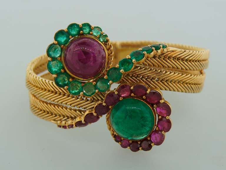 Stunning bracelet created in France in the 1960's. Beautiful floral design - two stylized flowers "kissing" each other. Features an approximately 8.55-ct ruby and 7.26-ct emerald cabochons accented with faceted rubies and emeralds. Total