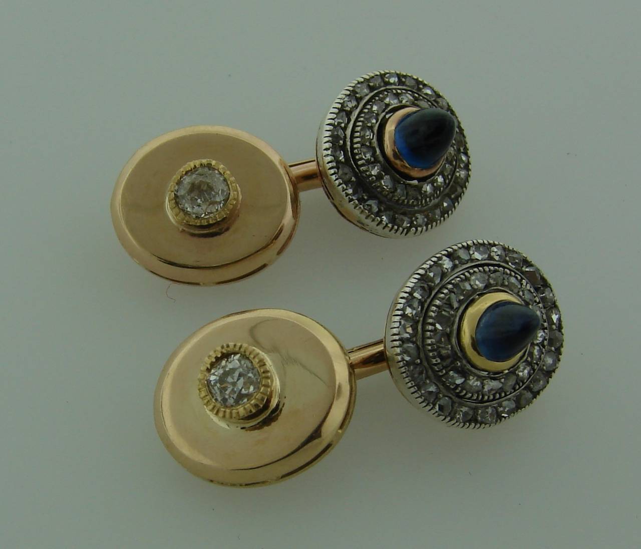 Elegant and classy pair of cufflinks created in the 1900's. Features two sugar-loaf sapphires, two cushion cut diamonds set in rose gold and silver. The sapphires are framed with two rows of rose cut diamonds.

The oval discs are 1/2