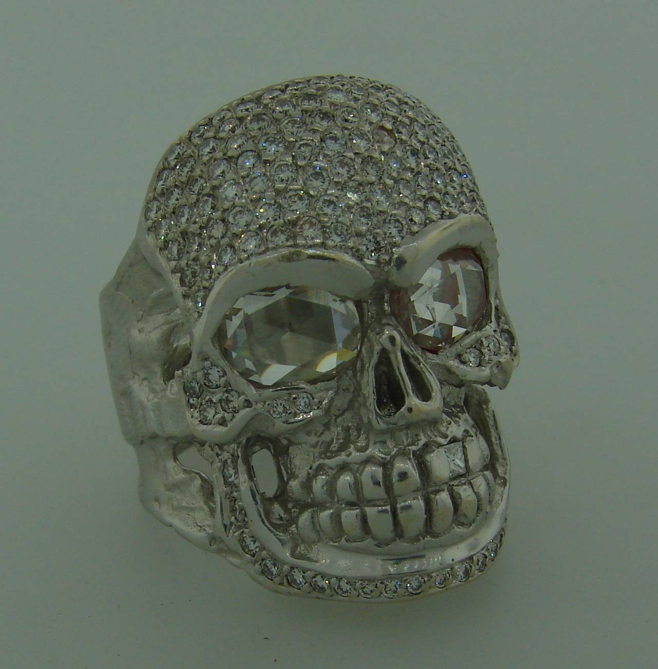 Outstanding diamond skull ring created by a renown Hollywood designer Loree Rodkin. Features two rose cut diamonds as the skull's eyes, round brilliant cut diamonds all over the face and one princess cut diamond as its tooth. 
The rose cut diamonds