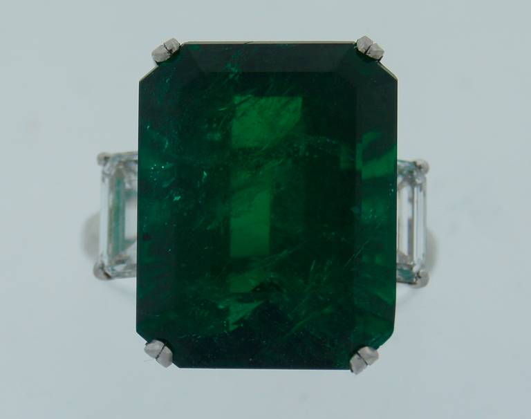 Classy and timeless three-stone ring created by Tiffany & Co. Features a beautiful 15.02-ct Zambian emerald flanked with two emerald cut diamonds on the sides set in platinum. The emerald comes with a GIA emerald origin report (please see picture