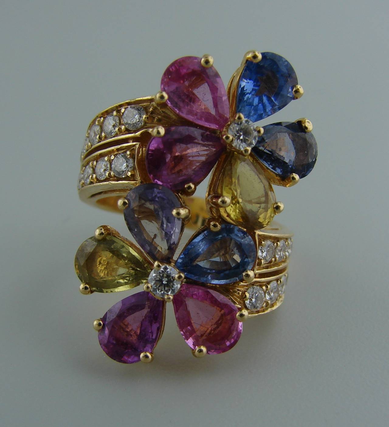 Colorful feminine ring created by Bulgari in Italy in the 1990's. Features two flowers "kissing" each other made of multi-color sapphires and accented with round diamonds set in 18k yellow gold.
Ten pear-shape multi-color sapphires -