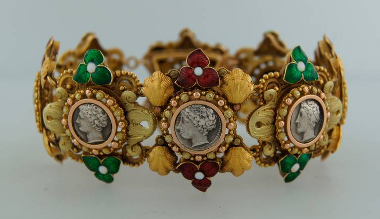 Beautiful and colorful bracelet created in France in the 1950s. Features eight silver coins with a man's and a woman's profile framed in two-tone yellow gold and accented with color enamel.
The bracelet measures 7 x 1.25 inches and fits up to
