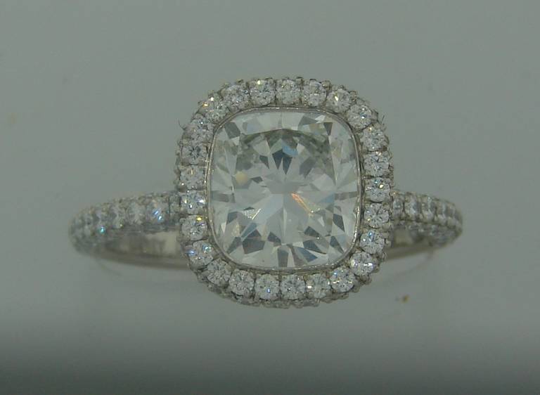 Stunning diamond solitaire ring with pave diamonds created by De Beers in the 2000's. It features a 2.24ct cushion cut diamond (G color, VS1 clarity) set in platinum and accented with pave diamonds. Diamond total weight is 3.21 carats. The cushion
