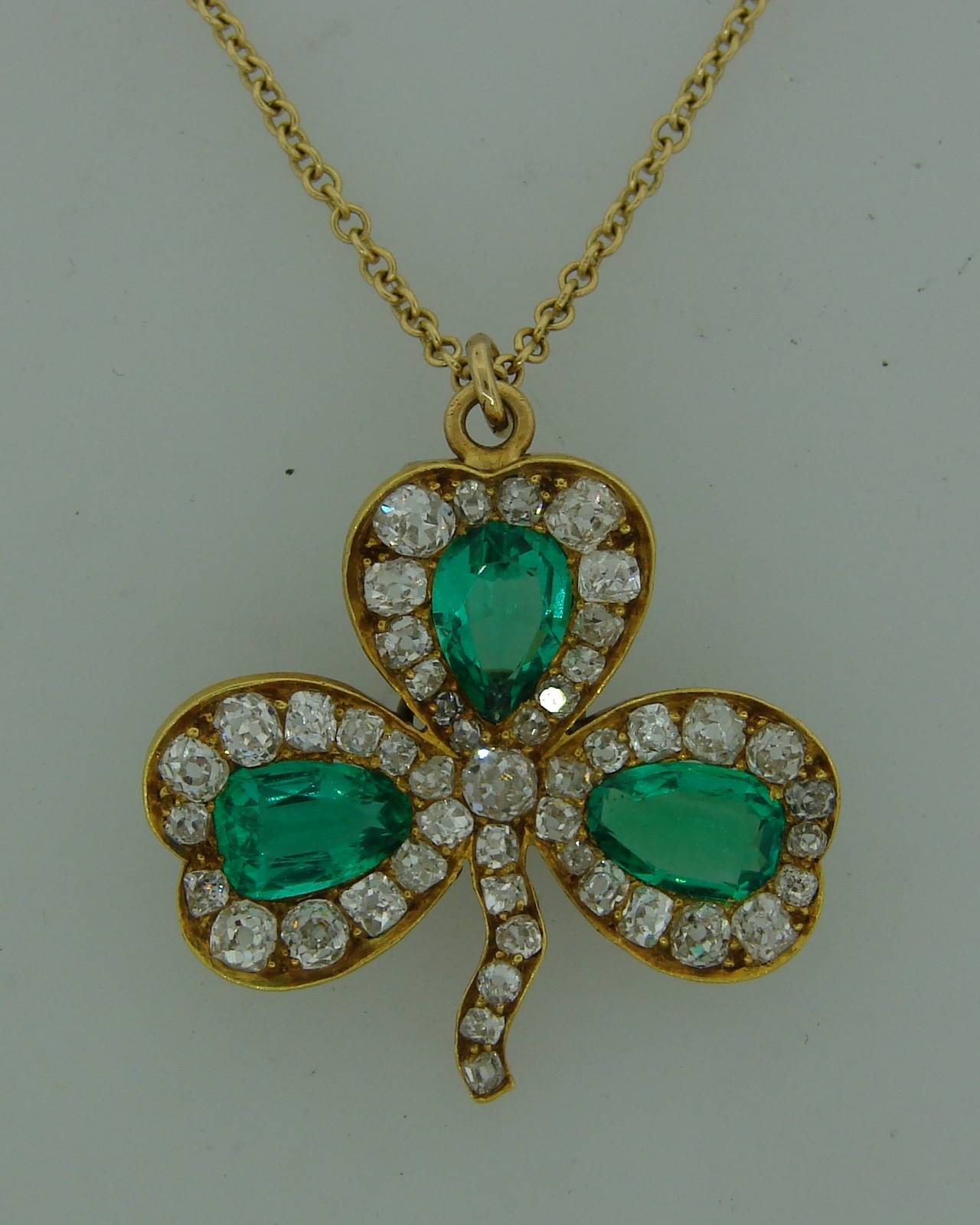 Adorable diamond & emerald clover pendant created by J.E. Caldwell in the 1930's. Features three pear-shape emeralds accented with old mine and cushion cut diamonds set in 14k yellow gold (tested). The pendant measures 1