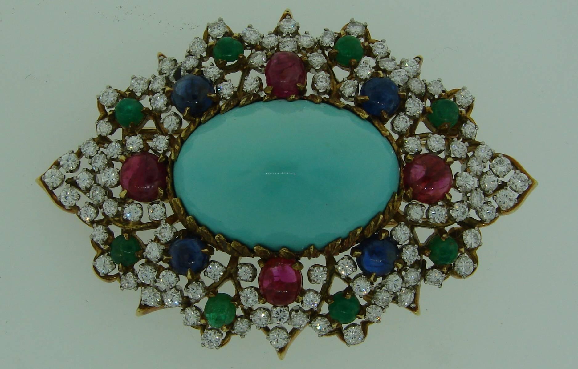 Gorgeous colorful brooch created in the 1970s. Features a beautiful turquoise embedded in a diamond and multi-gem frame. The stones are set in 18k (tested) yellow and white gold. The gems are ruby, emerald and sapphire cabochons, the diamonds are
