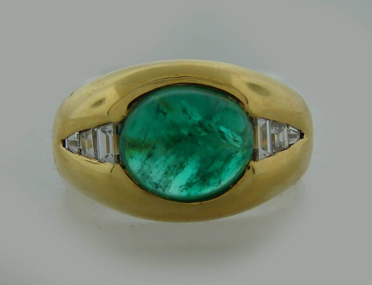 Chic and elegant ring created by Bulgari in the 1970's. Features a cabochon emerald set in 18k yellow gold and accented with trapeze cut diamonds. The emerald measures 9.26 x 7.67 x 5.65 mm and weighs approximately 2.88 carats. The diamond total