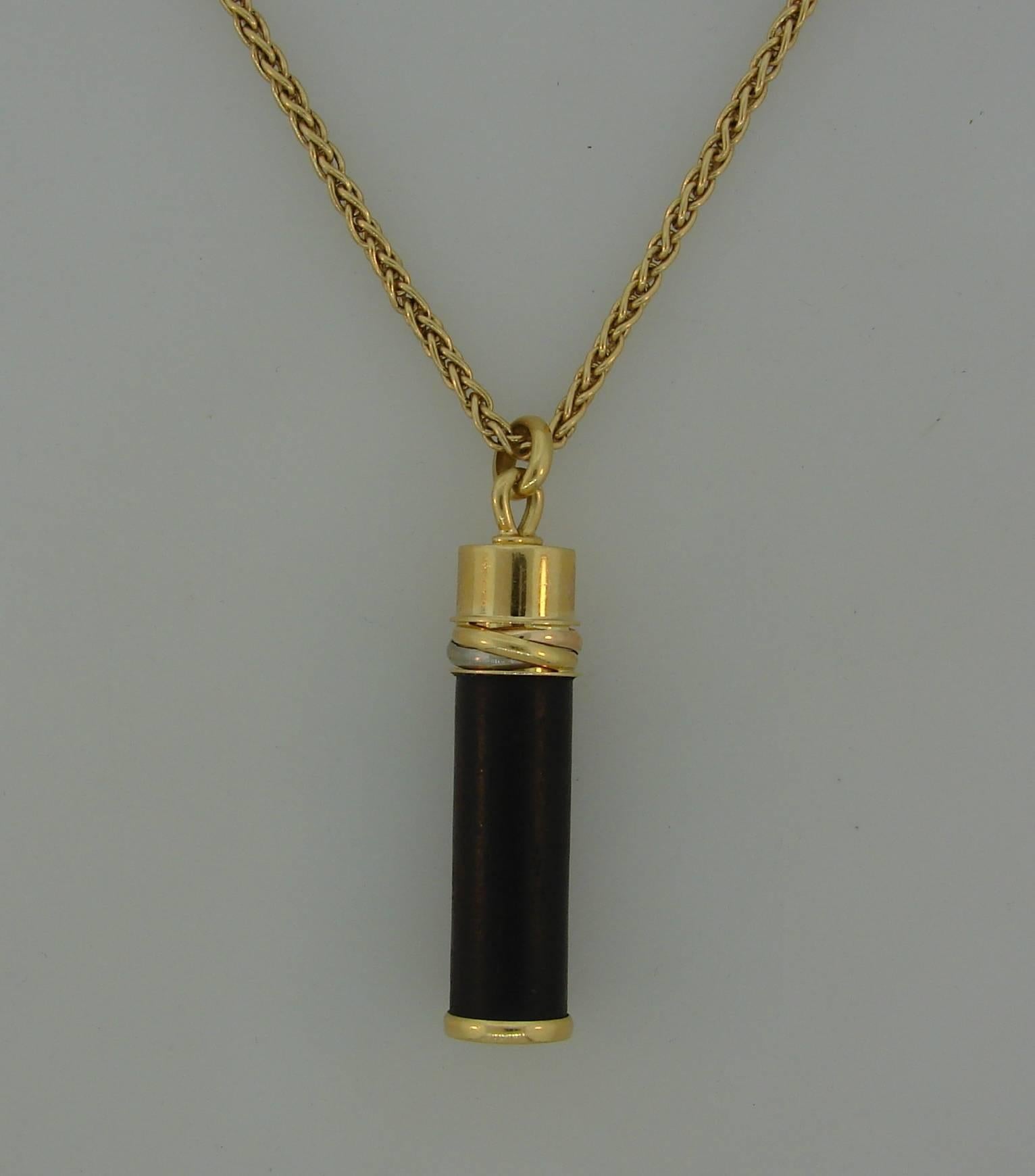 Lovely Trinity pendant created by Cartier in France in 1993. It belongs to  Touch Wood Collection and is made of 18 karat yellow, white and rose gold and wood. 
The pendant measures 1-3/8 x 3/8 inches, the chain is 16-1/2 inches long and 1/16 inch