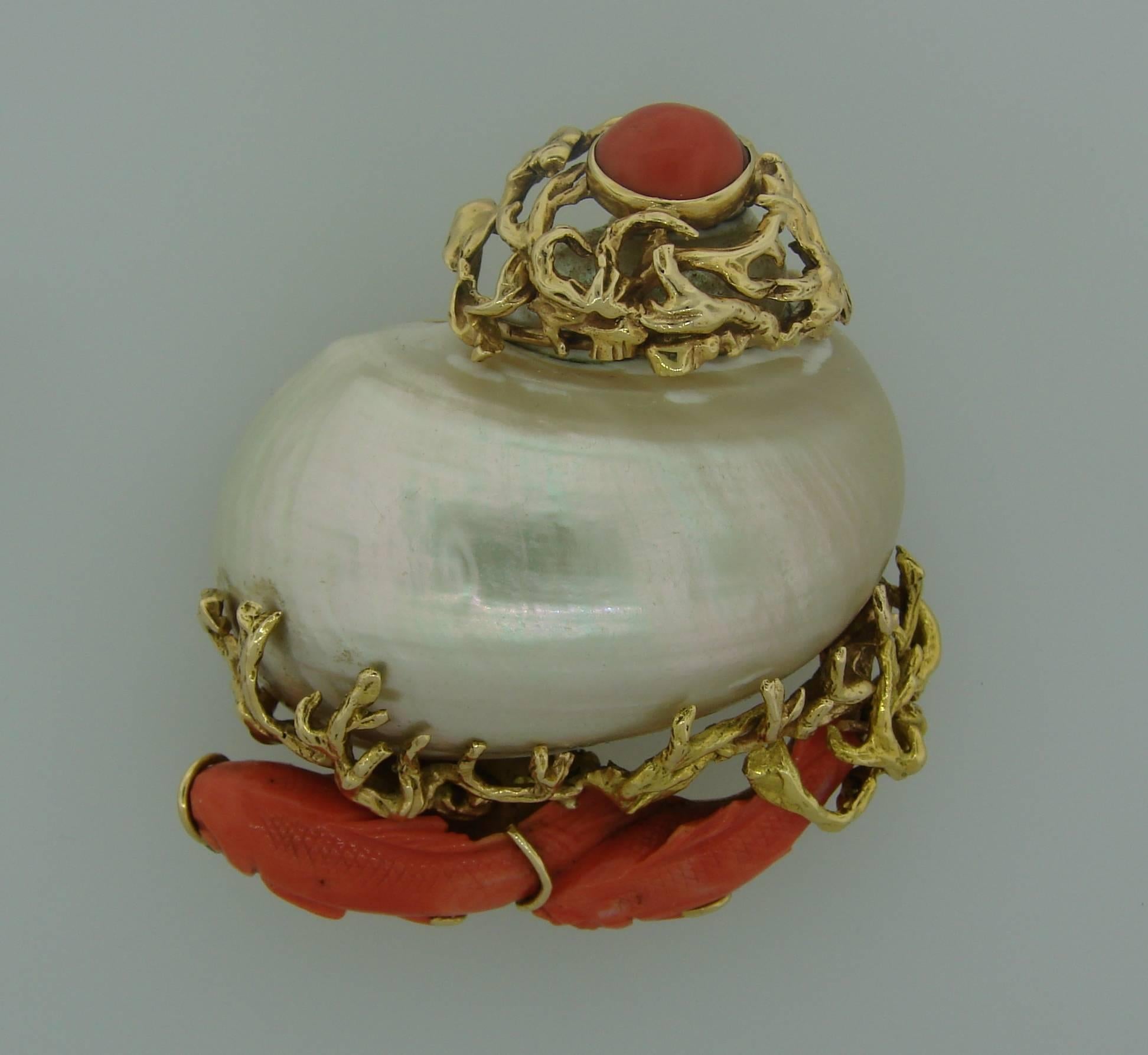 Prominent and colorful brooch created by Seaman Schepps in the 1950s. 
It features a white mother-of-pearl escargot shell set in 14 karat yellow gold and accented with carved and cabochon coral. 
The clip measures 2.5 x 2.25 x 1.25 inches and weighs