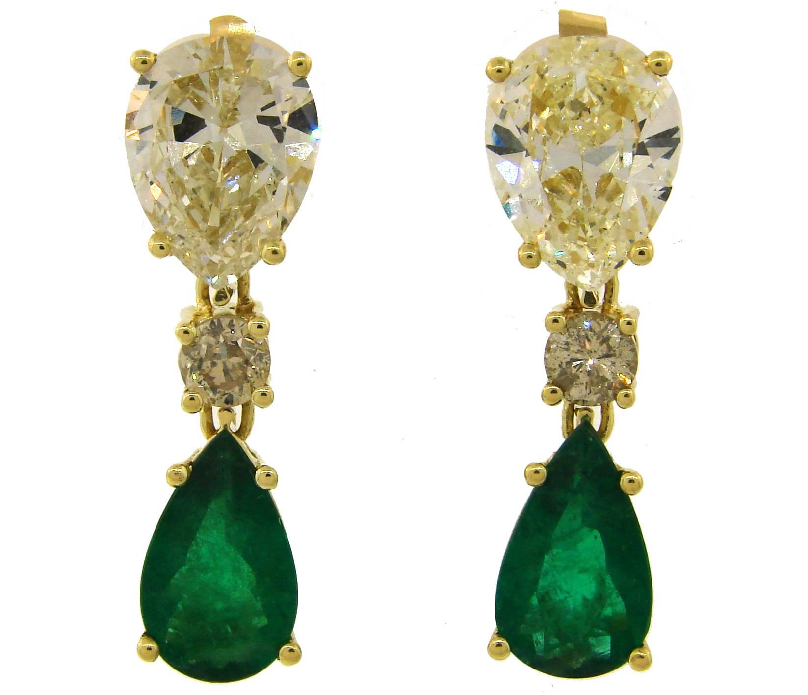 Classy and elegant pair of drop earrings that is a great addition to your jewelry collection. 
Feature a pear-shaped diamond and emerald connected with a round brilliant cut diamond set in 18 karat (tested) yellow gold. One earring holds 3.74-carat