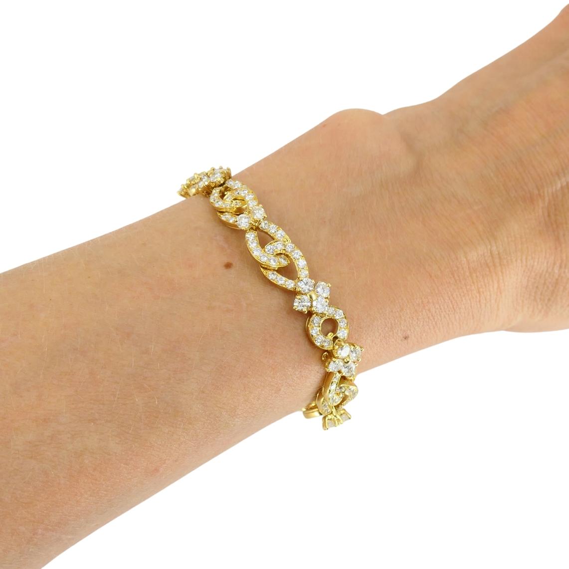Ce bracelet vintage Van Cleef & Arpels est réalisé en or jaune 18 carats et présente un motif répétitif de maillons ajourés sertis de diamants et de grappes en forme de fleurs. Chaque maillon incurvé est serti de petits diamants ronds de taille