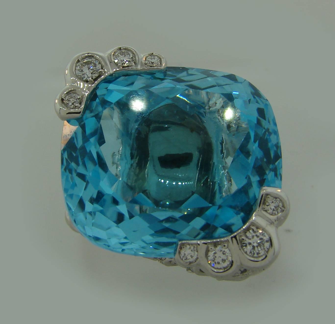 Stunning cocktail ring created by French company Piaget. Features a beautiful cushion cut blue topaz set in 18 karat white gold and accented with round brilliant cut diamonds (total weight approximately 1 carat). 
The blue topaz measures 20.07 x