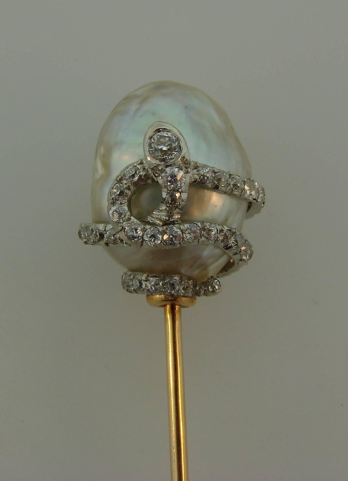 Exquisite hat stick pin created by J. E. Caldwell in the 1910's. It features a natural baroque pearl wrapped with a snake. The snake is made of platinum and set with Old European cut diamonds (J-L color, VS2-SI1 clarity, total weight approximately