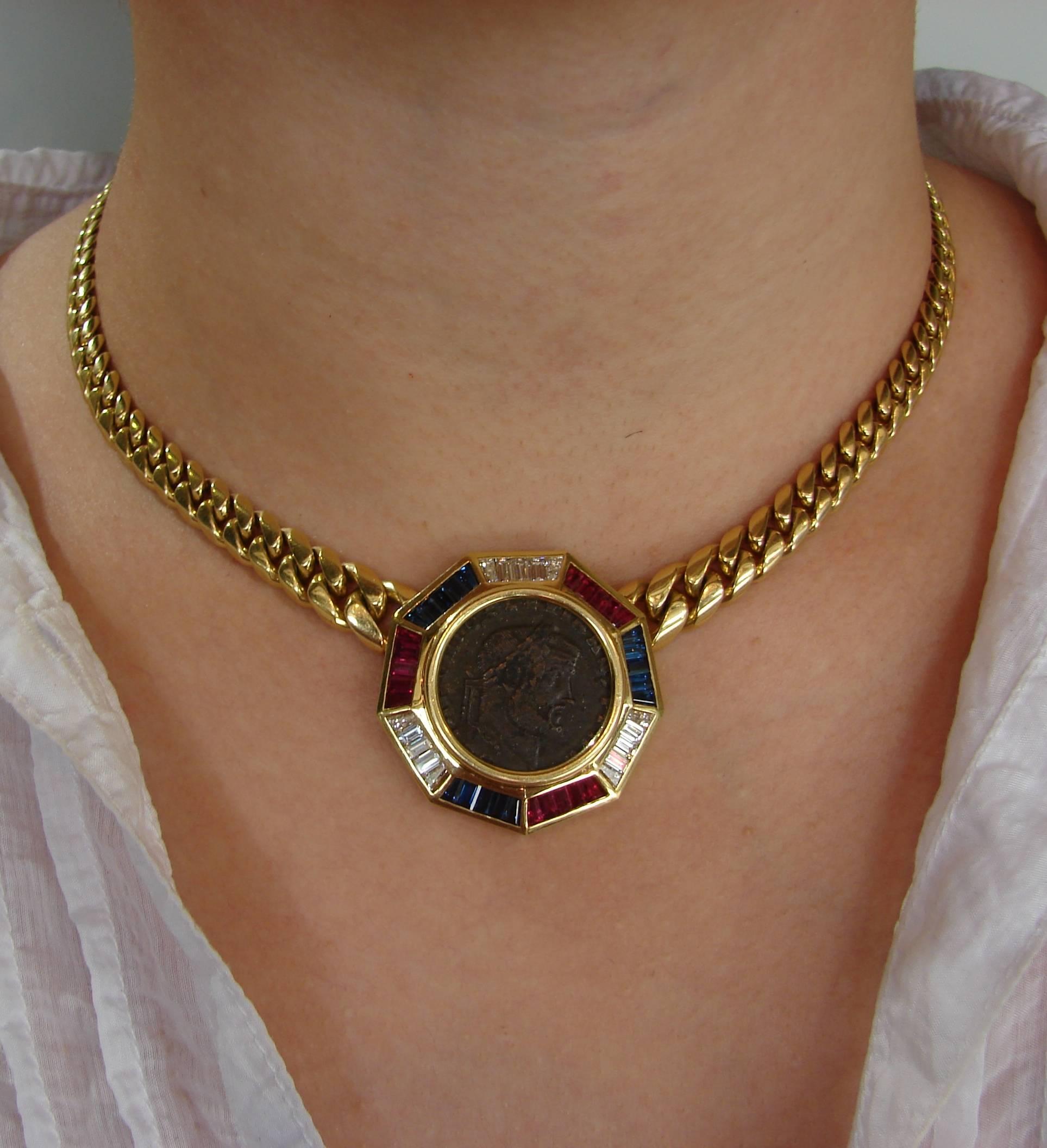 Signature Bulgari coin pendant necklace created in the 1970s. It features an ancient Maxentius bronze coin set in 18 karat yellow gold and accented with baguette cut diamonds, rubies and sapphires. 
The necklace is 16 inches (40 cm) long and weighs