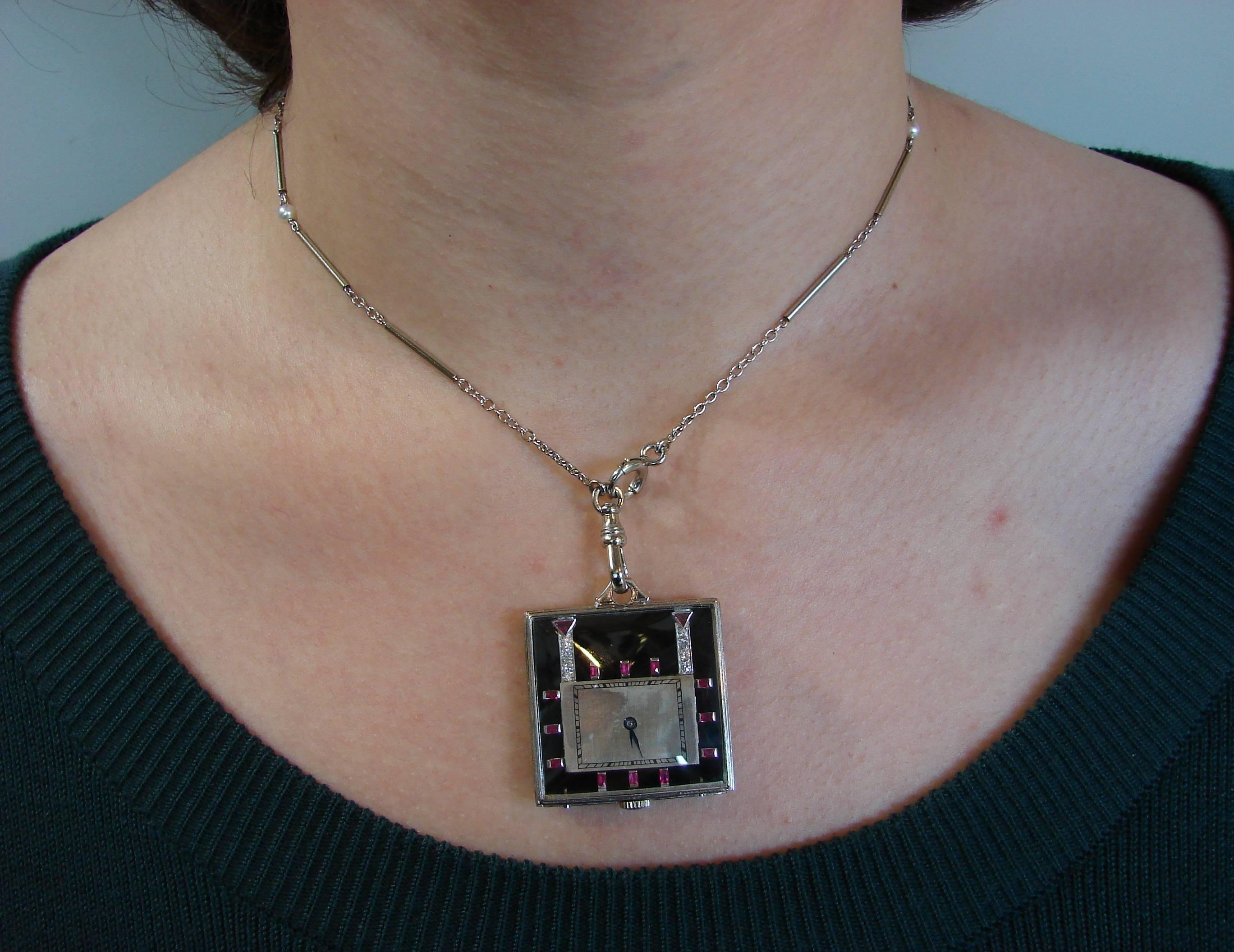 Classy Art Deco Revival watch pendant created in the 1950's. Made of platinum and black onyx and accented with round brilliant cut diamonds and rubies.
The watch is mechanical and manual wind. 
The pendant measures 1.25 x 1.25 inches (3.2 x 3.2 cm),