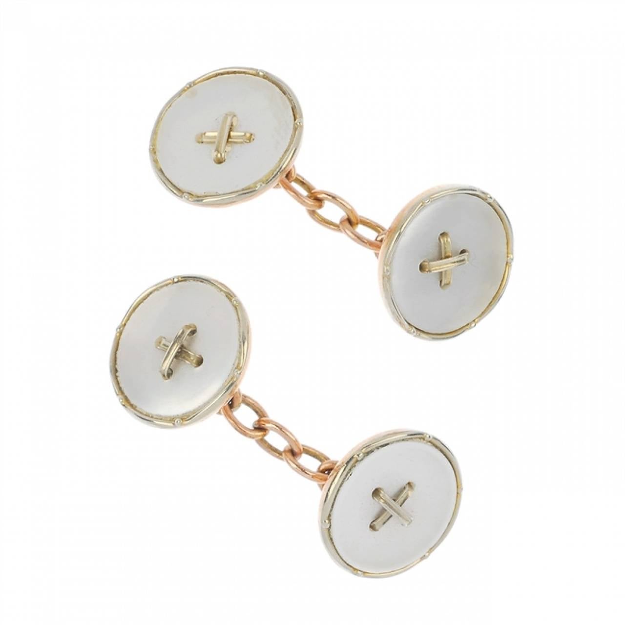 An early 20th century gold mother-of-pearl dress set, comprising cuff-links designed as two circular-shape mother-of-pearl discs, with central cross motif and connecting chain, with matching buttons and studs. Supplied with associated case. 9ct