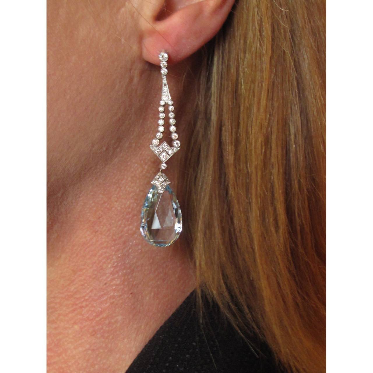 A pair of platinum Art Deco earrings, each comprising a briolette cut aquamarine, estimated to weigh 14.92 carats in total, suspended from a geometric diamond top, estimated to weigh 1.35cts in total, H colour, SI clarity.