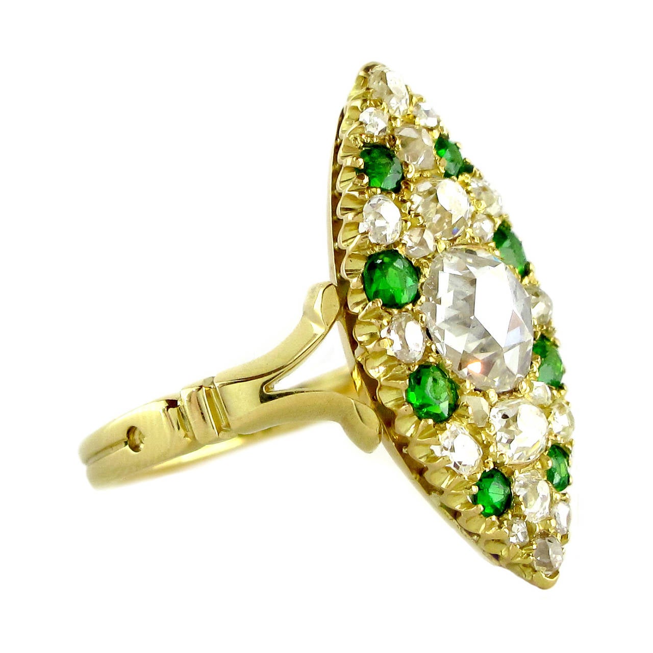 A Victorian diamond and demantoid garnet marquise/navette shaped panel ring, circa 1890. Comprising a central rose cut diamond, estimated to weigh 0.56 carats, set within a twenty-eight stone diamond and demantoid garnet surround. The stones are