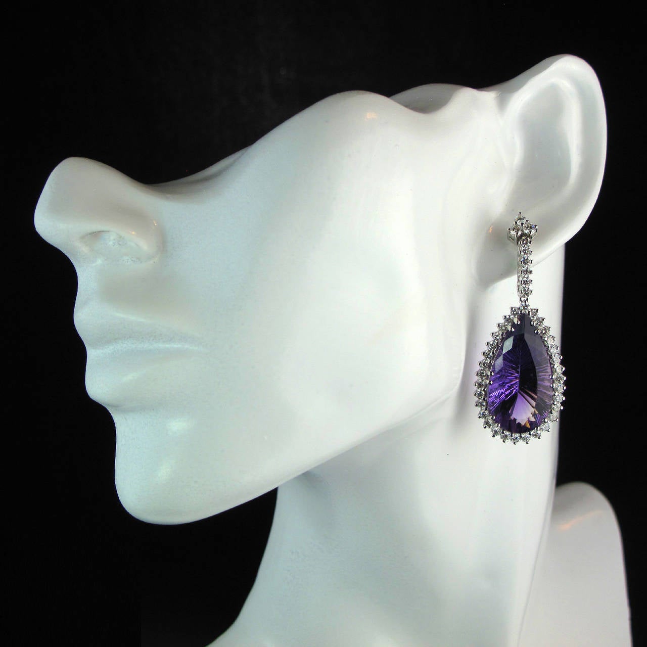 A pair of exquisite 18kt white gold ear pendants, each comprising a large oval amethyst drop within a round brilliant cut claw set surround, suspended from a diamond drop. 

Approximately 5cm long, 2cm wide. 

Total diamond weight approximately