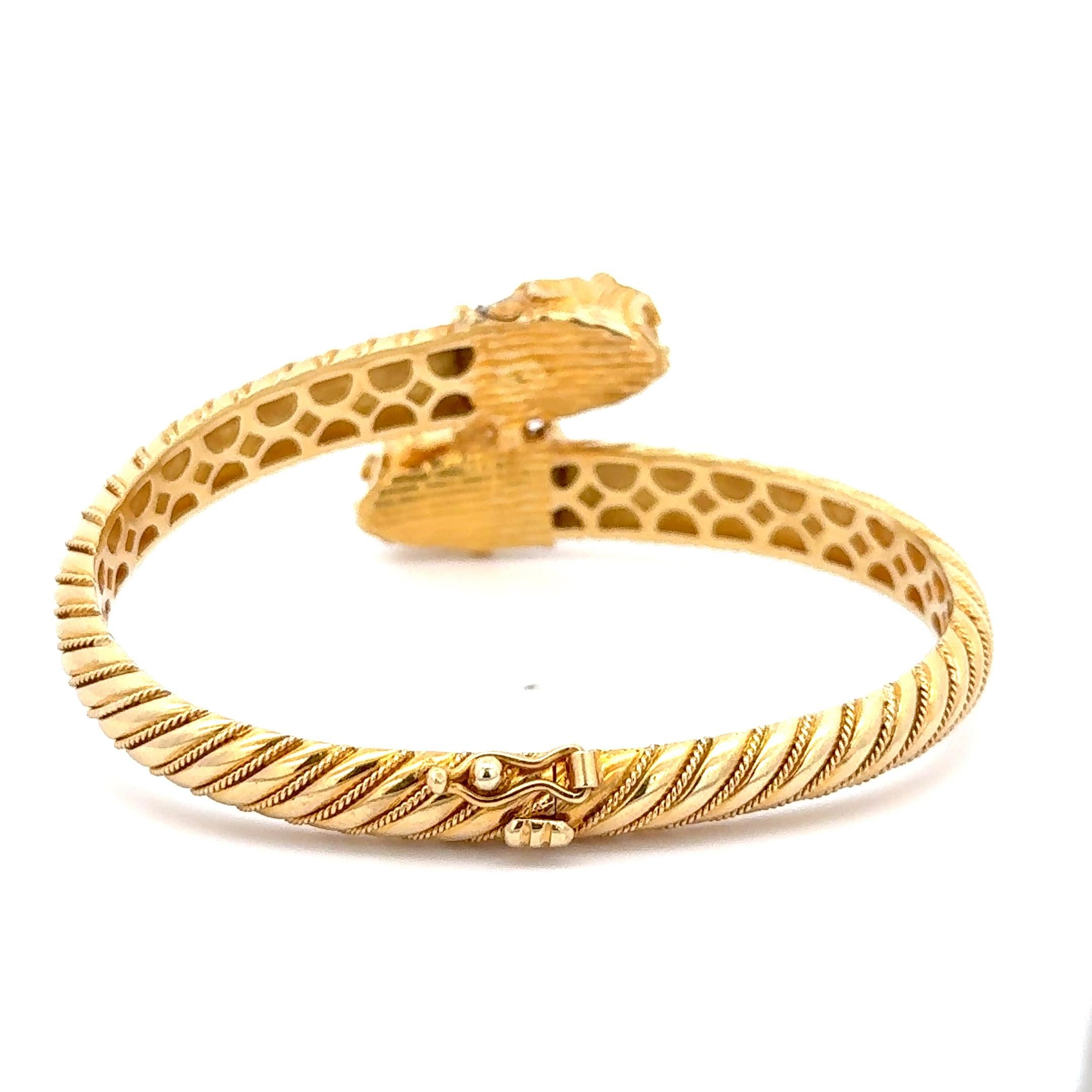 Pulsera Bypass Cabezas de León de Oro Amarillo de 18 quilates. La pulsera presenta rubíes como ojos de los leones, acentuados por aproximadamente 0,50ctw de diamantes. La pulsera tiene una circunferencia interior de 7 pulgadas y pesa 47 gramos. 