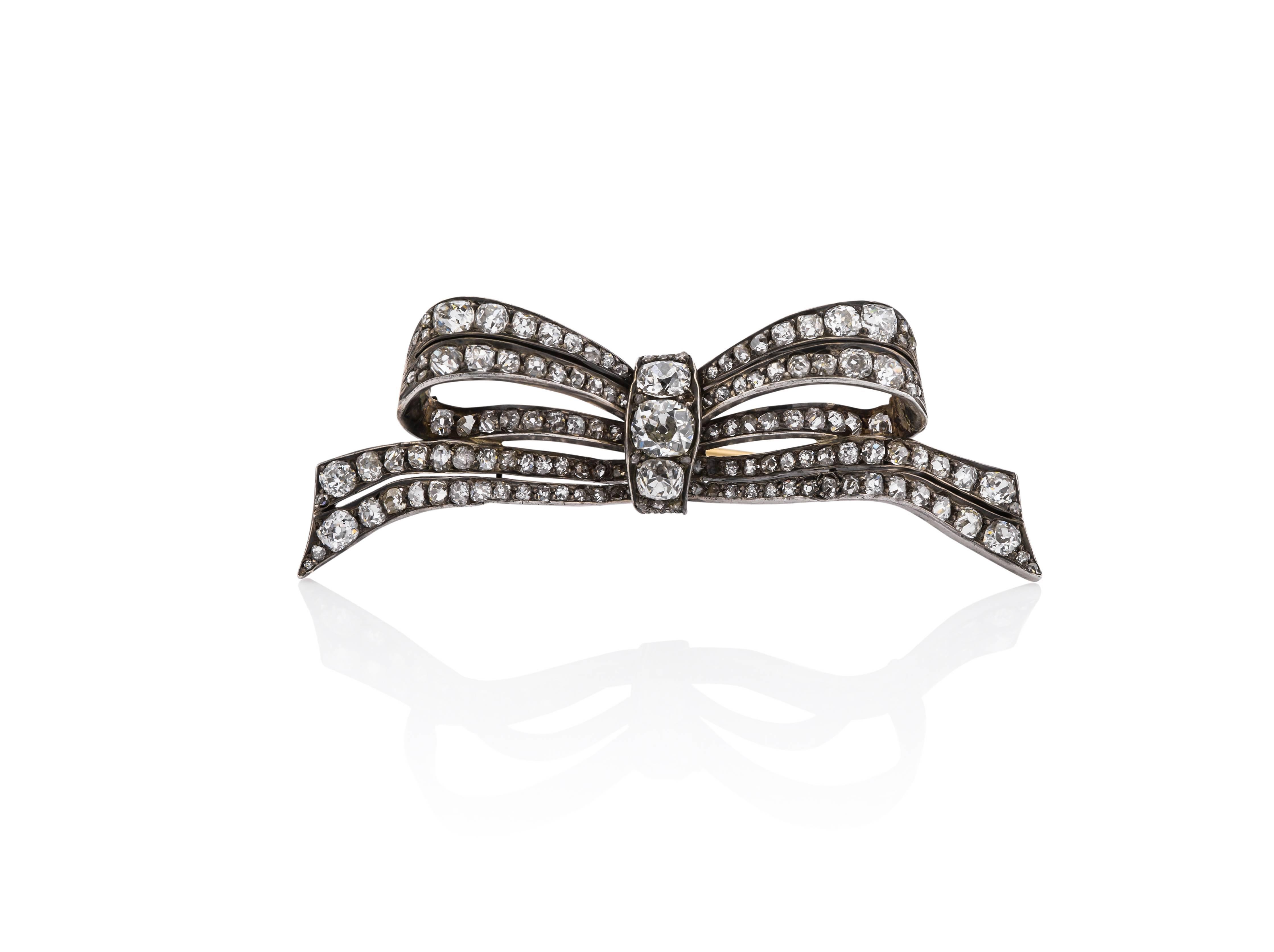 Elegant Silver and Rose Gold Bow Pin.  
Appears to be from a tiara. 
6.75ctw Diamonds
130 Diamonds
Old mine cut diamonds; 
center diamond .90cts
side diamonds .45cts each 
diamonds are of SI/2 clarity and K/L color