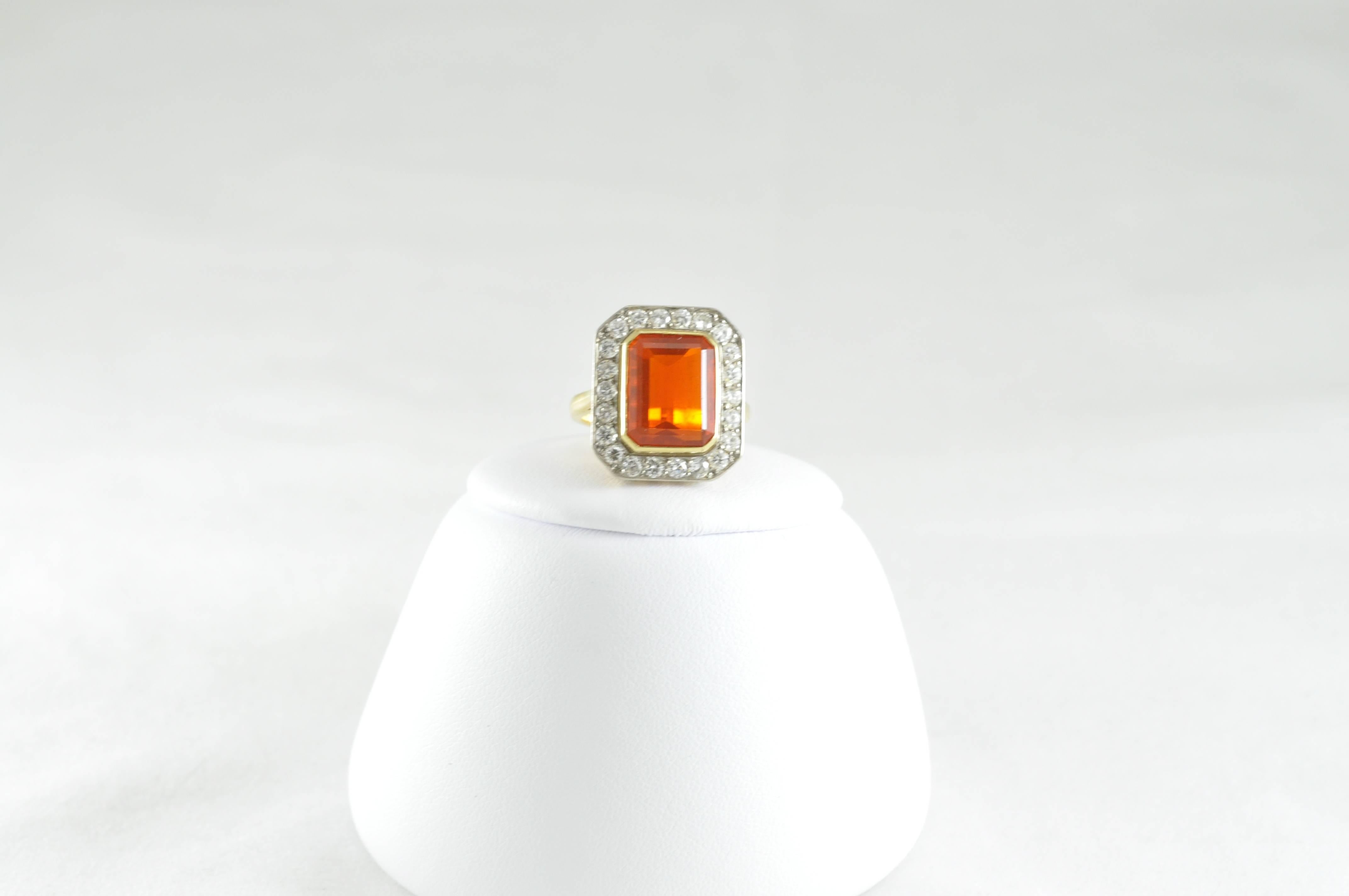 Stunning approximately 4.48ct Emerald-cut Fire Opal surrounded by 1.32ct round Diamonds set in 18k yellow gold. The ring is currently a size 7.75 but could be sized as needed. The ring is stamped S and D for Steele and Dolphin; a Crown insignia