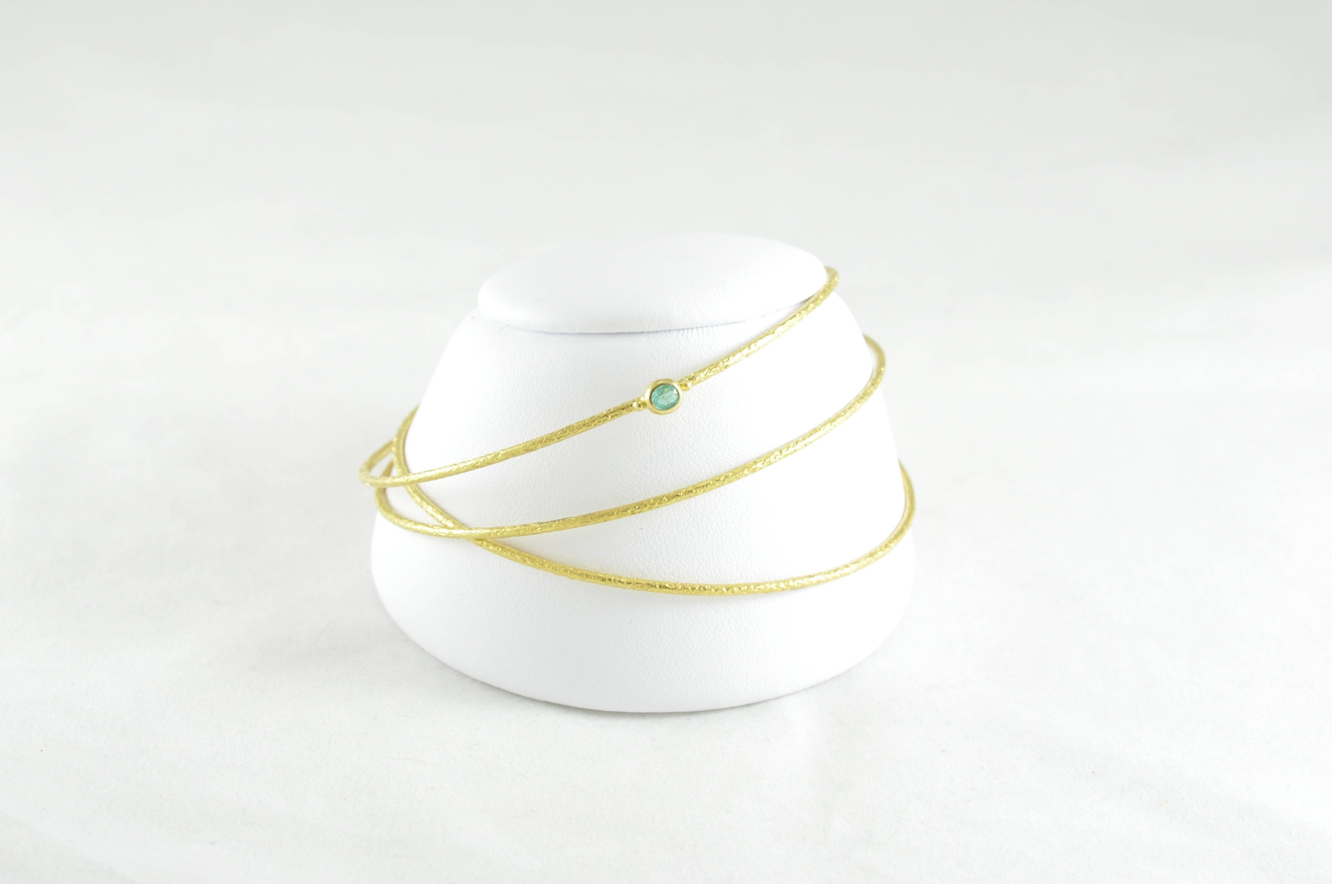 20k Gold Hammered Bangle set designed by Kimarie. Two of the Bangles are plain and one is adorned with a natural, bezel-set Emerald. The bracelets have a diameter of 2.75 inches each. Big impact look for such delicate, yet durable, quality