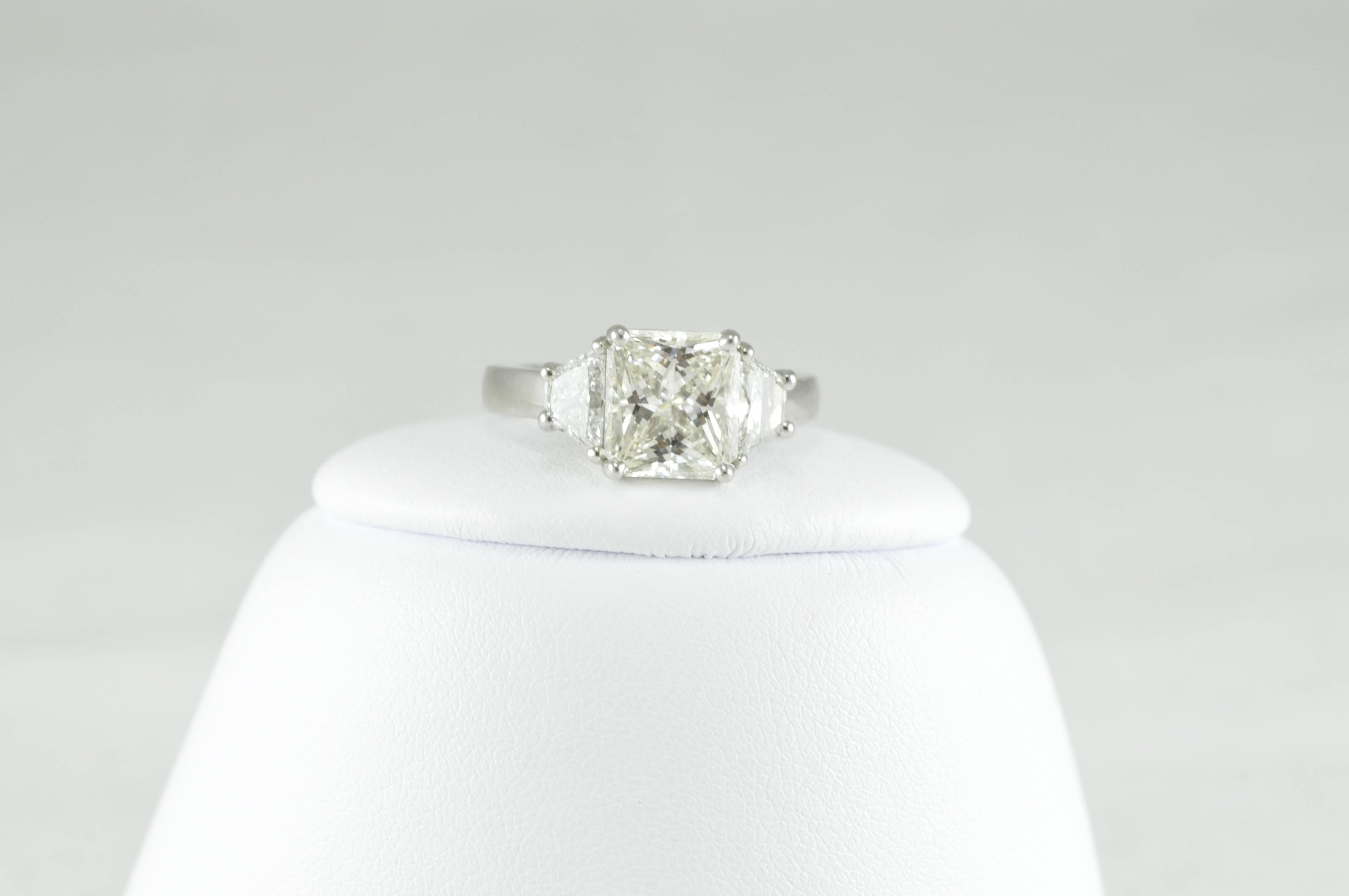 STUNNING Three Stone Platinum and Diamond Ring! 
3.28CT Radiant Cut Diamond J/SI1.  9.18x8.33x5.31mm. Polish Very Good. Symmetry Good.  Florescence Medium Blue.  
1.05CT Trapezoids
GIA Cert Upon Request
Stamped PLAT
Sized 6.25 and can be sized to
