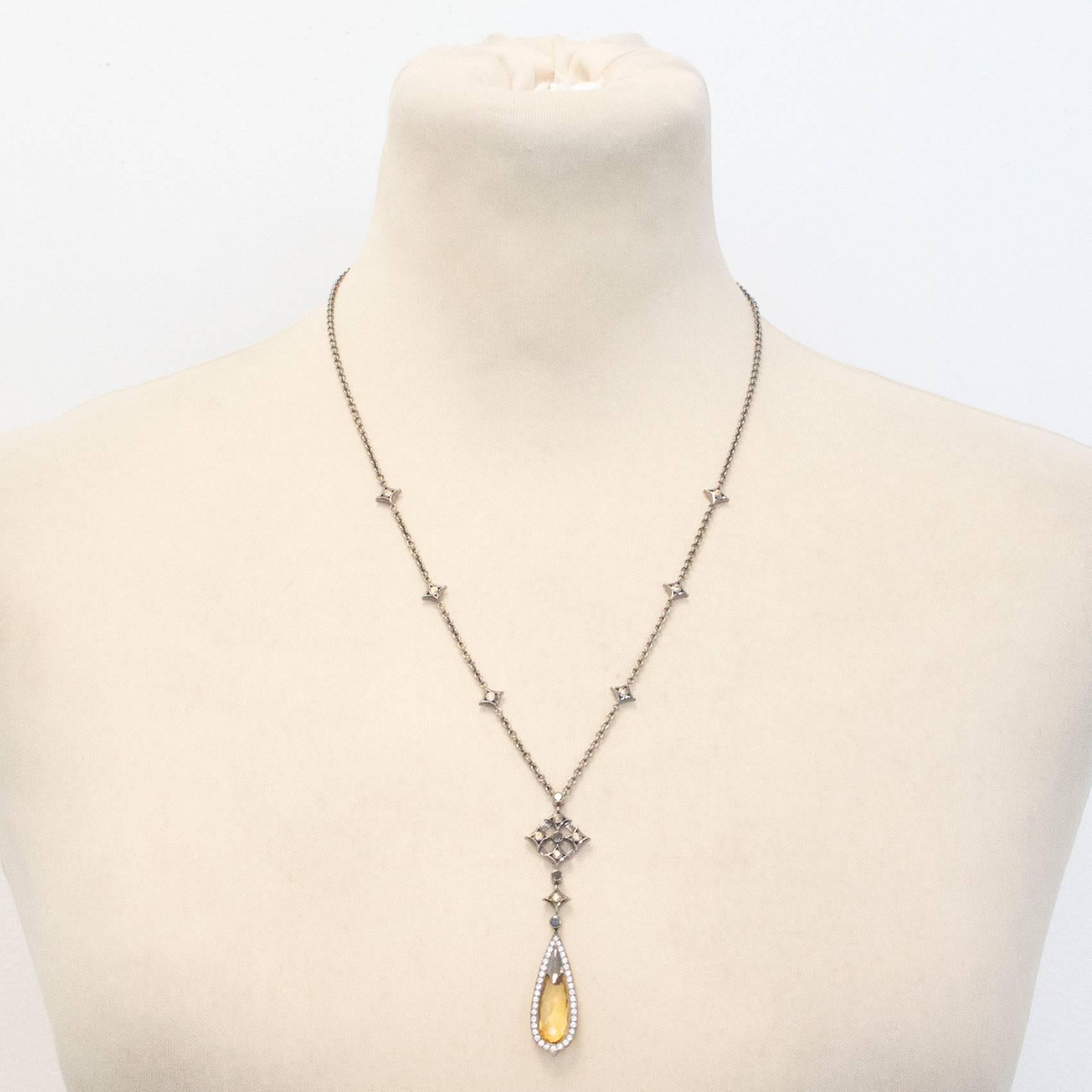 Beautiful Theo Fennell black and silver necklace with citrine/yellow sapphire stone drop pendant.  Citrine/Yellow sapphire surrounded by diamonds. Cross motif at top of drop pendant with small yellow sapphires on chain of necklace.

This necklace is