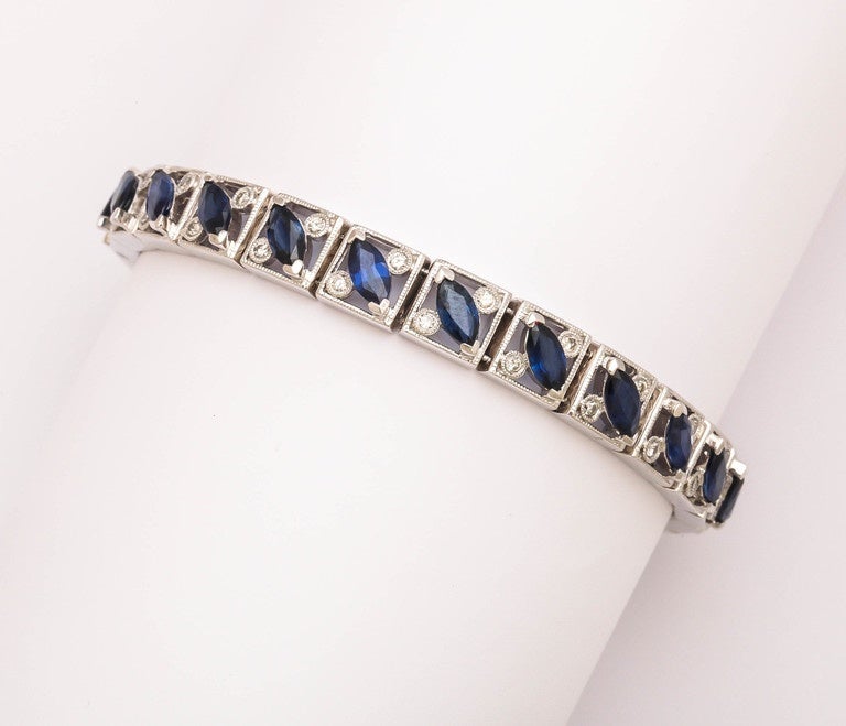 Stunning and classical 14 kt white gold bracelet with 23 beautiful blue marquise sapphires totaling 9.77 cts. Also there are 46 round white diamonds on either side of the sapphires, total weight is .97 ct. The bracelet is 7 1/2 inches long and 3/8