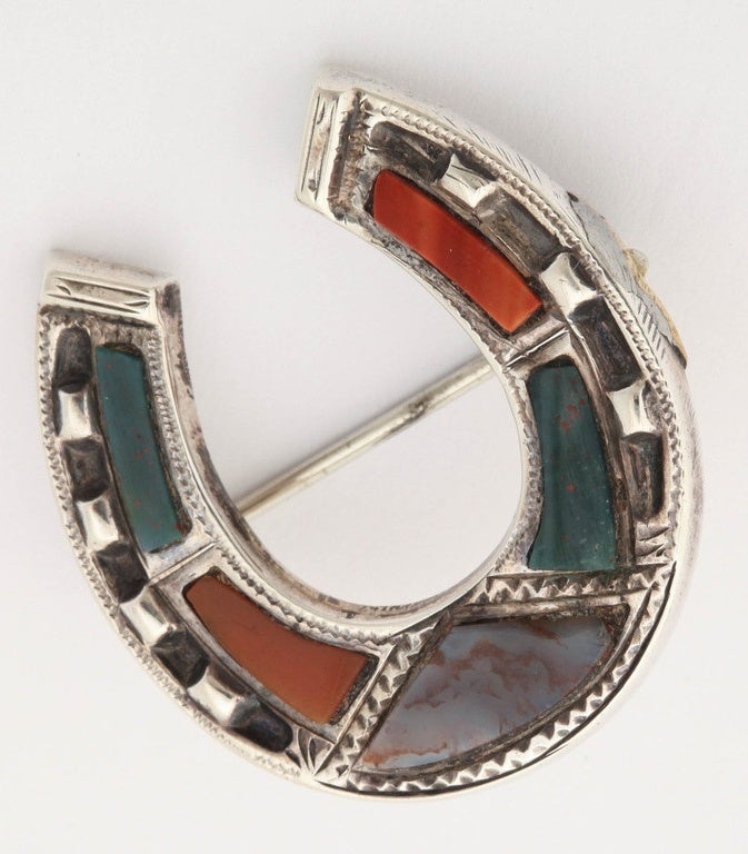 A great quality Scottish silver horse shoe shaped brooch. Set with individual cut and polished agate panels. The engraving around the pin adds elegance and texture. Very collectable, most distinctive an immensely wearable, would look great on a hat.
