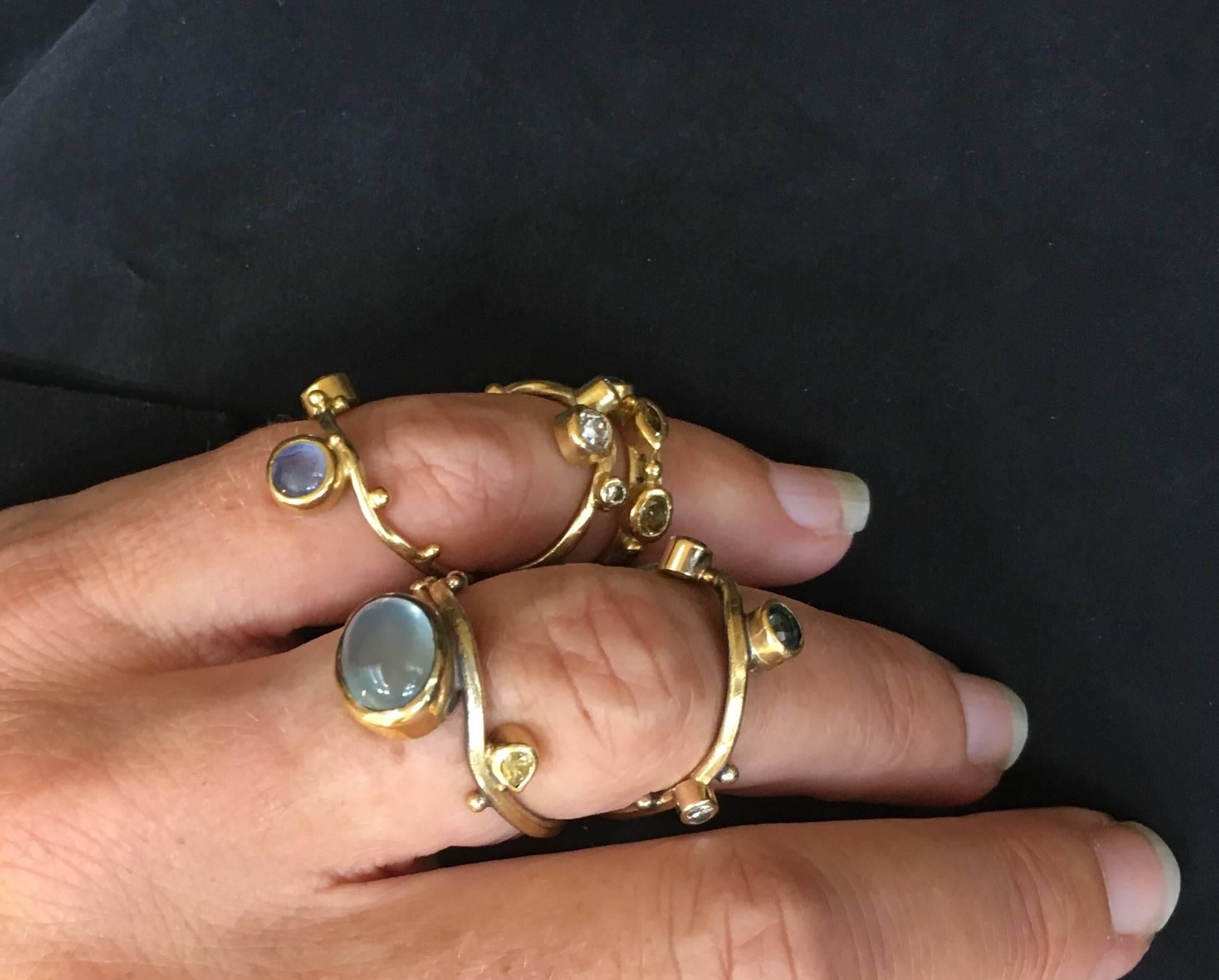 You wear this unique ring in the middle of your finger, with a ringband on each side of the knuckle.
It is made in oxidized silver, 18, 22 and 24 karat gold with a blue aquamarine, green sapphire, natural yellow 0.12 ct. pear shaped diamond, 0.02