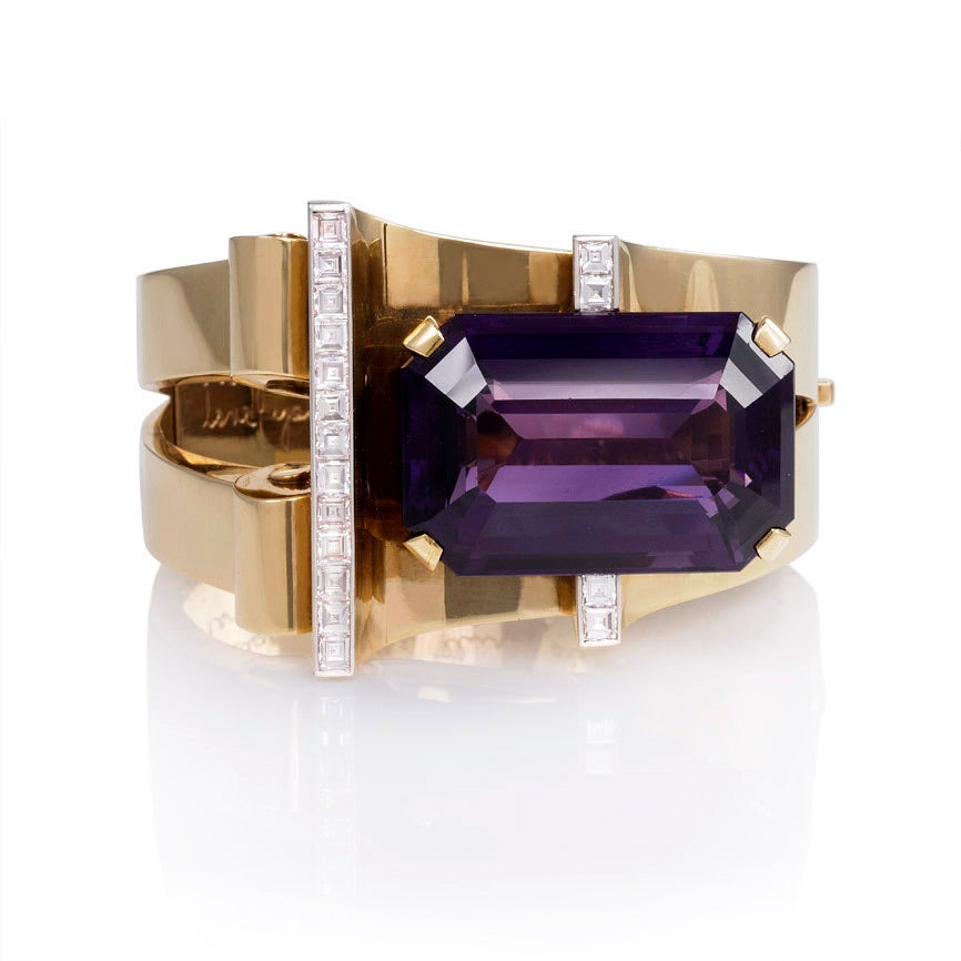 A Retro gold, amethyst, and diamond bangle bracelet, the open tapered front featuring curved and scroll motifs set with a large rectangular amethyst and square-cut diamond accents, in 14k.  Designed by MGM's Gilbert Adrian for Joan Crawford. 