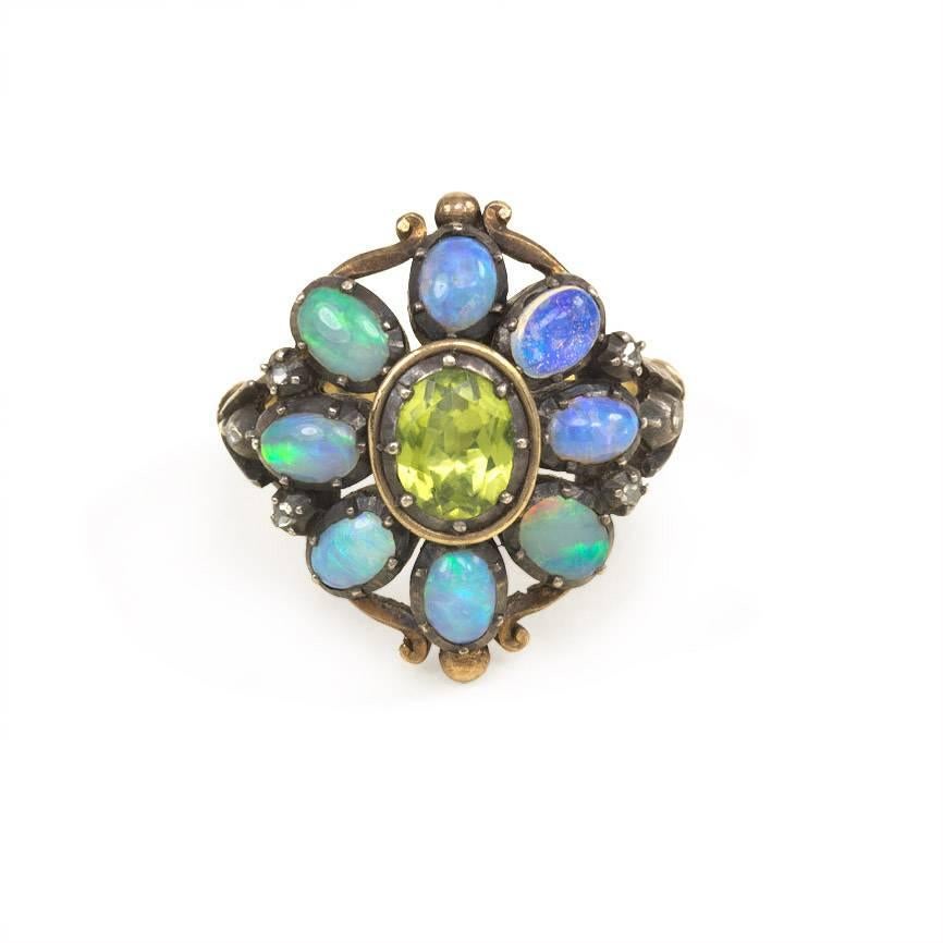 An opal and peridot cluster ring featuring an oval peridot center in a surround of opals decorated with scrollwork and rose diamond accents, to the openwork shoulders, in silver and 18k gold.  Portugal.
Cluster measures approximately 3/4
