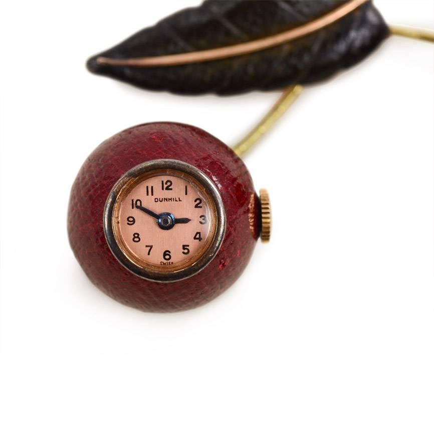 An Art Deco lapel watch/brooch designed as a pair of articulated cherries rendered in burgundy and green leather and inset with a watch and thermometer, in 18k gold. Dunhill movement, maker's poinçon for Georges Meyer, France #22130.