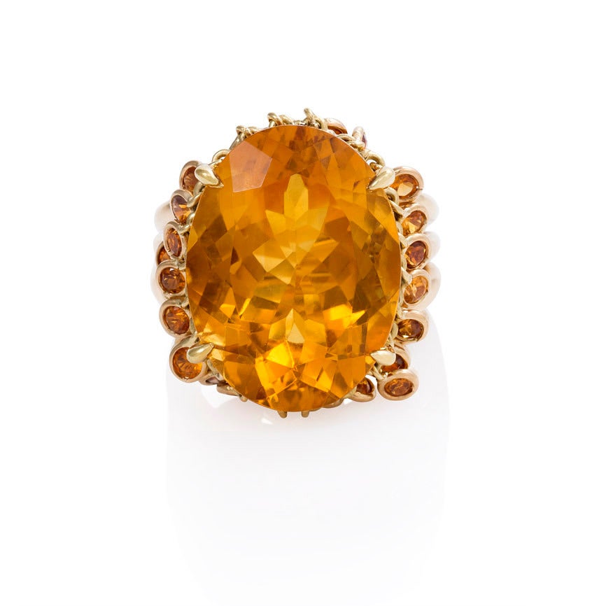 A Retro oval citrine cocktail ring surrounded by a fringe of articulated collet-set citrines, in 18k gold with openwork shoulders.