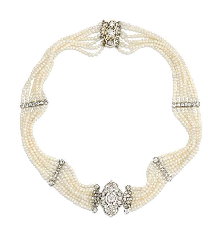 An Edwardian seed pearl and diamond choker, with matching pendant diamond earrings (atw. 1.70 ct.) of diamond foliate designs. The choker is comprised of seven rows of pearls, centering on an oval diamond plaque with diamond-set collets and leaves,