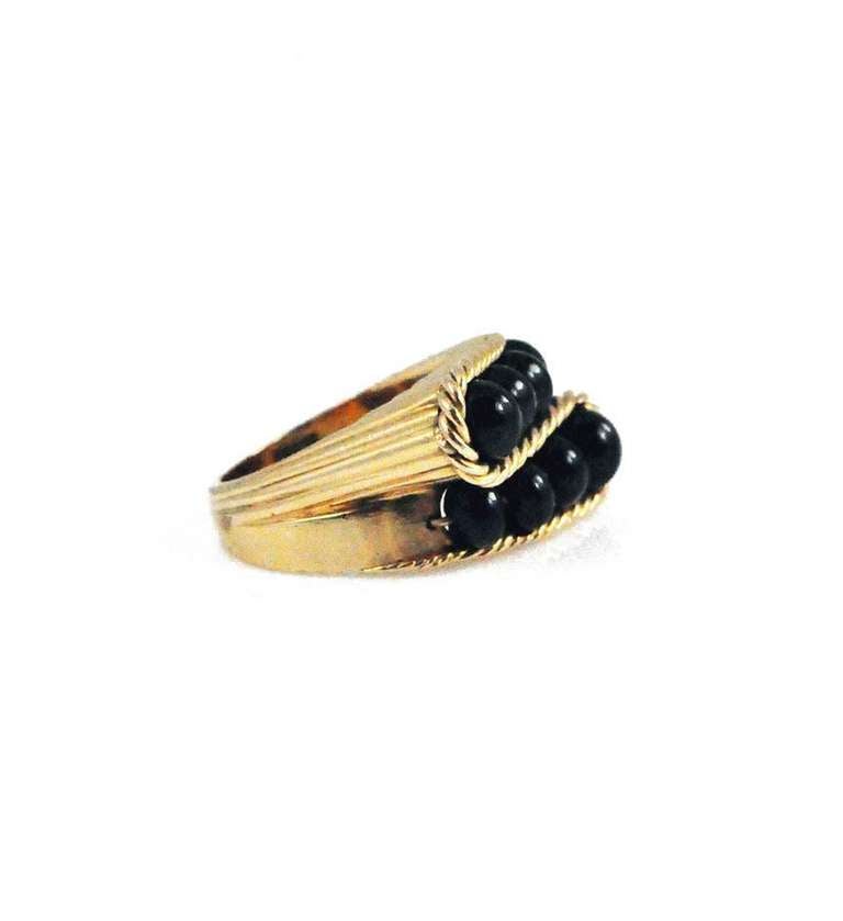 A Retro gold and onyx bead ring of crossover design in a ribbed setting, in 18k. France.
